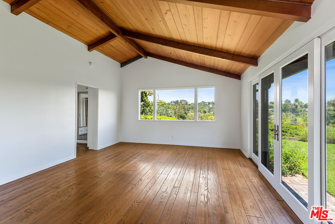 13238 Riviera Ranch Road Los Angeles, CA 90049 - Photo 15 of 28 an empty room with wooden floor and windows
