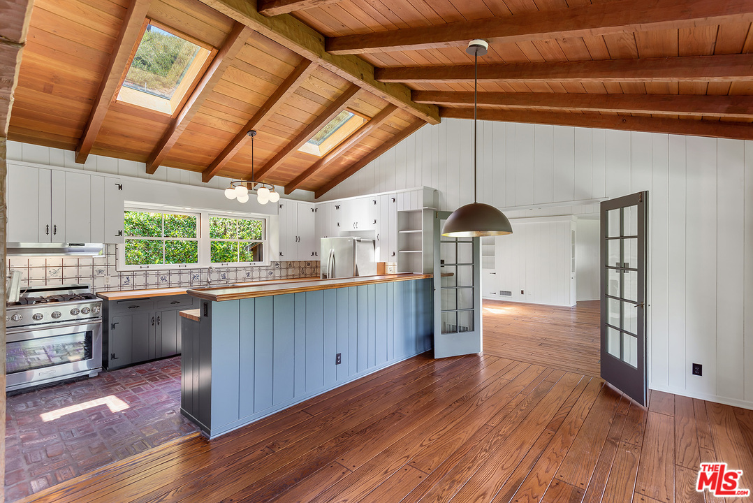 13238 Riviera Ranch Road Los Angeles, CA 90049 - Photo 9 of 28 a kitchen with stainless steel appliances granite countertop a sink a stove and wooden floors