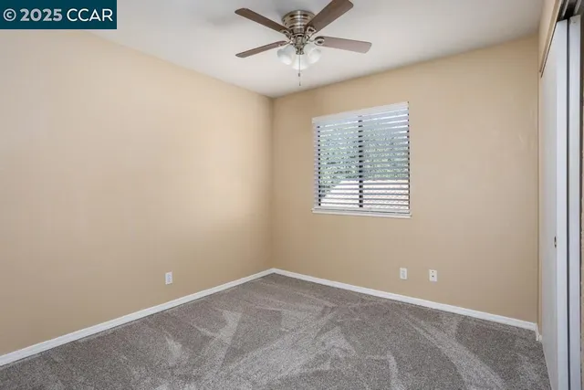 an empty room with windows and fan