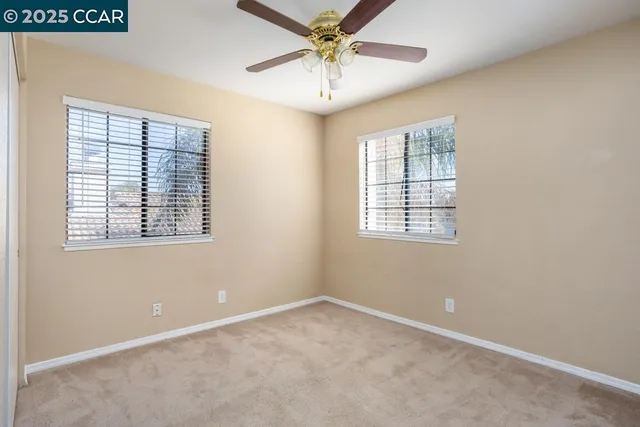 an empty room with windows and fan