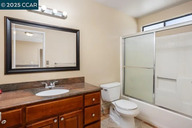 a bathroom with a granite countertop sink toilet a mirror and shower