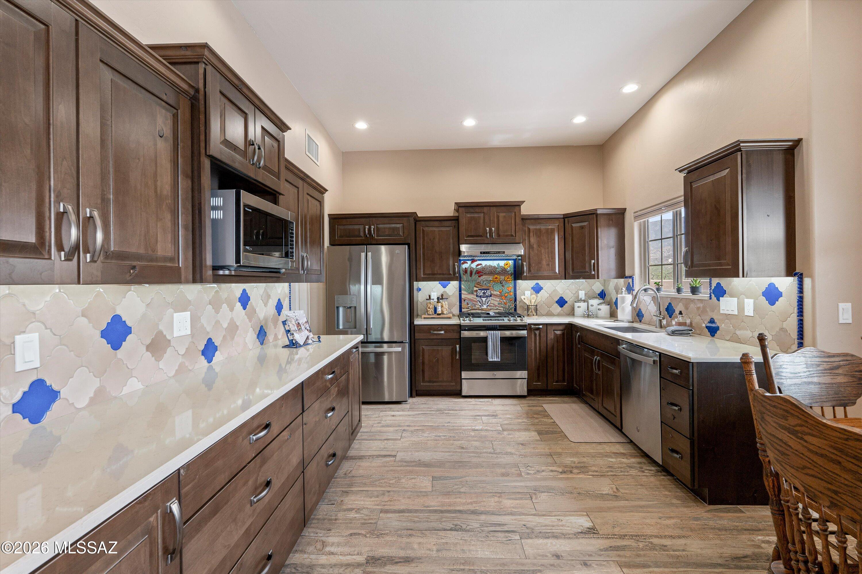 4760 East Wagon Train Road Tucson, AZ 85739 - Photo 21 of 38 a large kitchen with stainless steel appliances lots of counter space and wooden floor