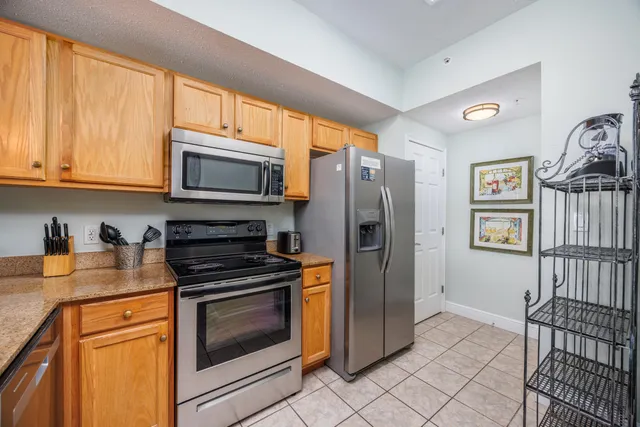 a kitchen with granite countertop a stove top oven microwave and refrigerator