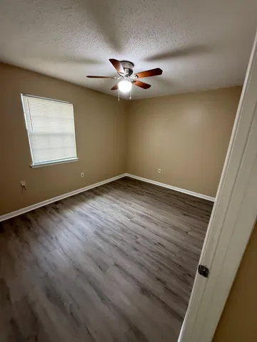 an empty room with wooden floor closet fan and windows