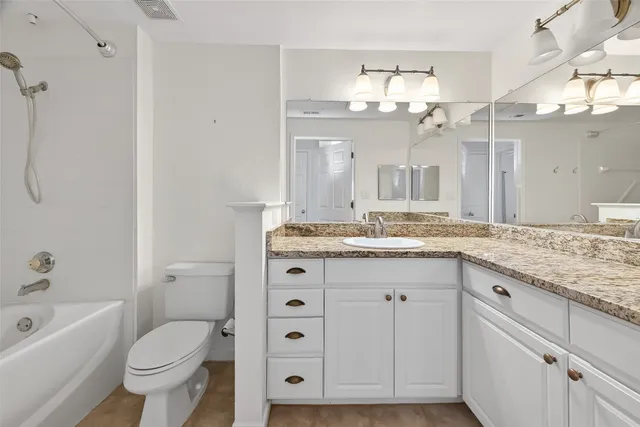 a bathroom with a granite countertop toilet a sink and a large mirror