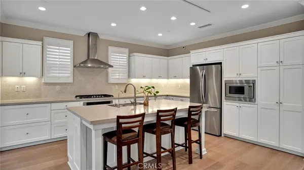 a kitchen with stainless steel appliances a dining table chairs stove and white cabinets