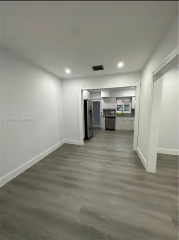 a view of a kitchen with refrigerator and wooden floor