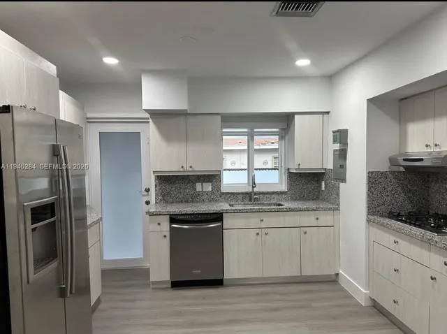 a kitchen with stainless steel appliances a refrigerator sink and microwave
