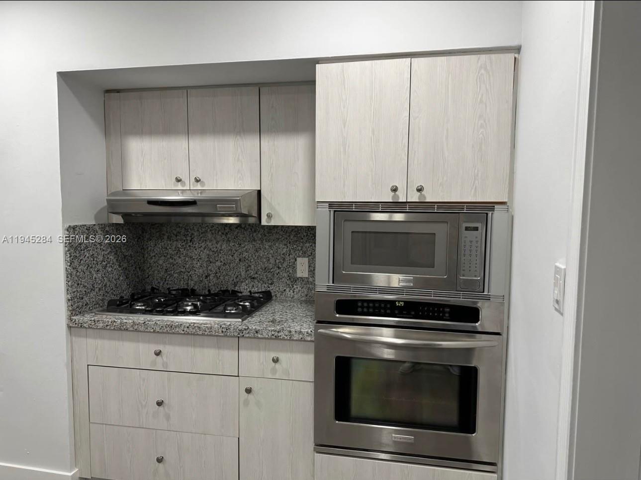 45 West 60th Street Hialeah, FL 33012 - Photo 5 of 11 a kitchen with granite countertop white cabinets and stainless steel appliances