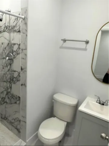 a white toilet sitting next to a bathroom sink and a shower
