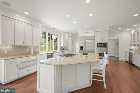 a large white kitchen with kitchen island white cabinets and stainless steel appliances