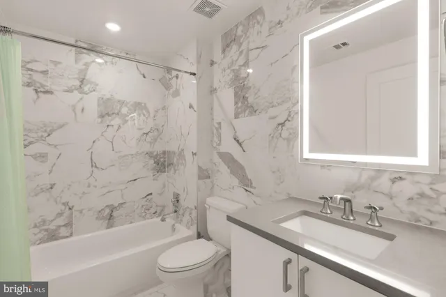 a bathroom with a granite countertop sink toilet and shower