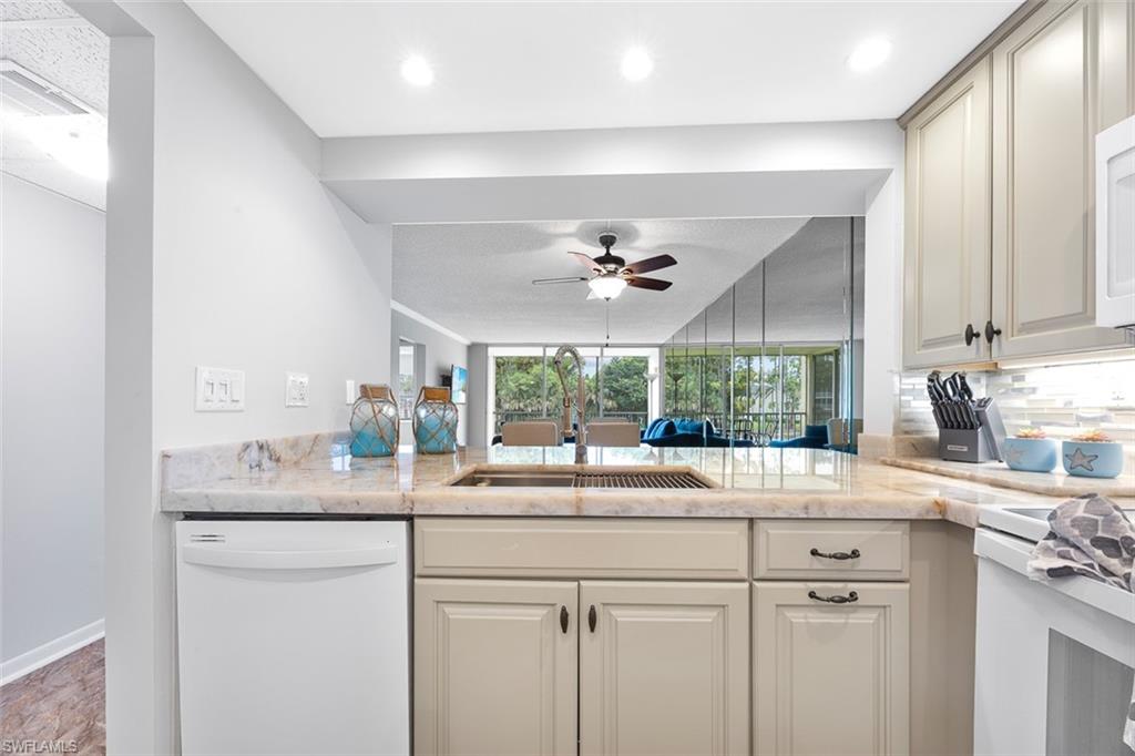 1083 Forest Lakes Drive, Unit 207 Naples, FL 34105 - Photo 6 of 21 a kitchen with kitchen island granite countertop a sink and a large window