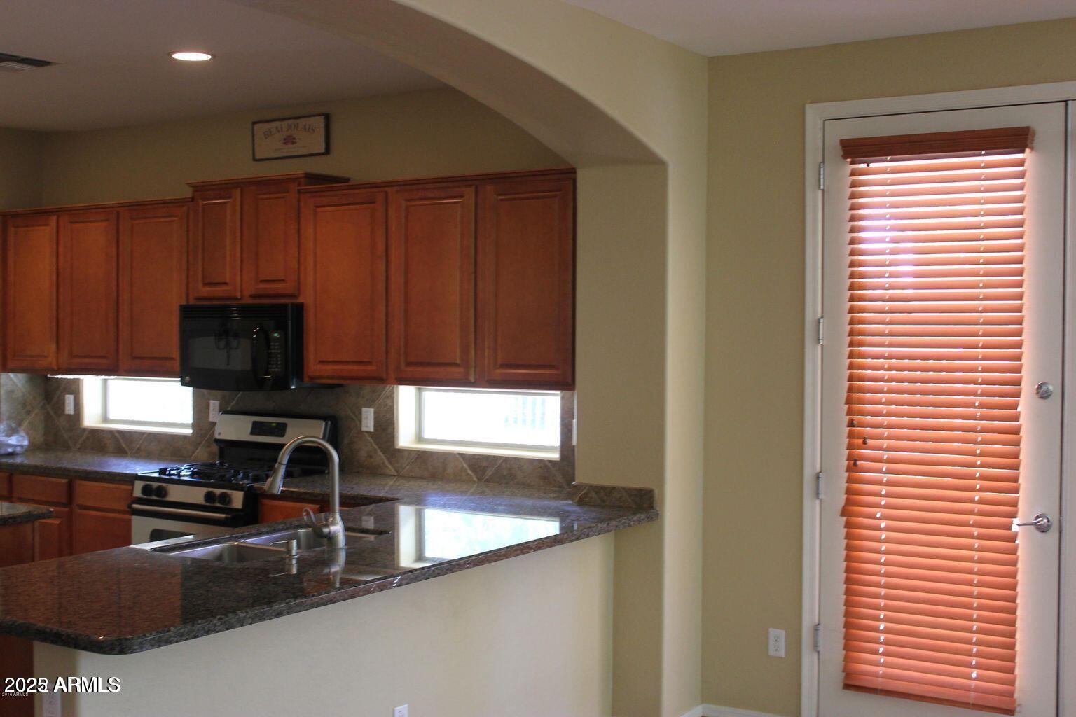 3897 East Powell Way Gilbert, AZ 85298 - Photo 4 of 9 a kitchen with wooden cabinets a sink and a stove