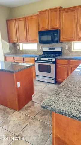 a kitchen with stainless steel appliances granite countertop a stove a sink and a microwave