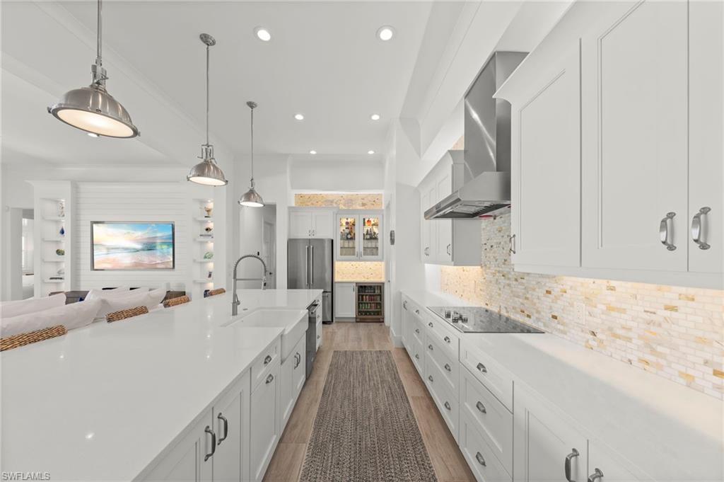 14785 Dockside Lane Naples, FL 34114 - Photo 11 of 50 Kitchen with white cabinets, hanging light fixtures, decorative backsplash, light wood-style floors, and high end refrigerator New KITCHEN PENDANTS (November 2018), New WINE REFRIGERATOR (November 2018), New KITCHEN INTERIOR PAINT (July 2023)