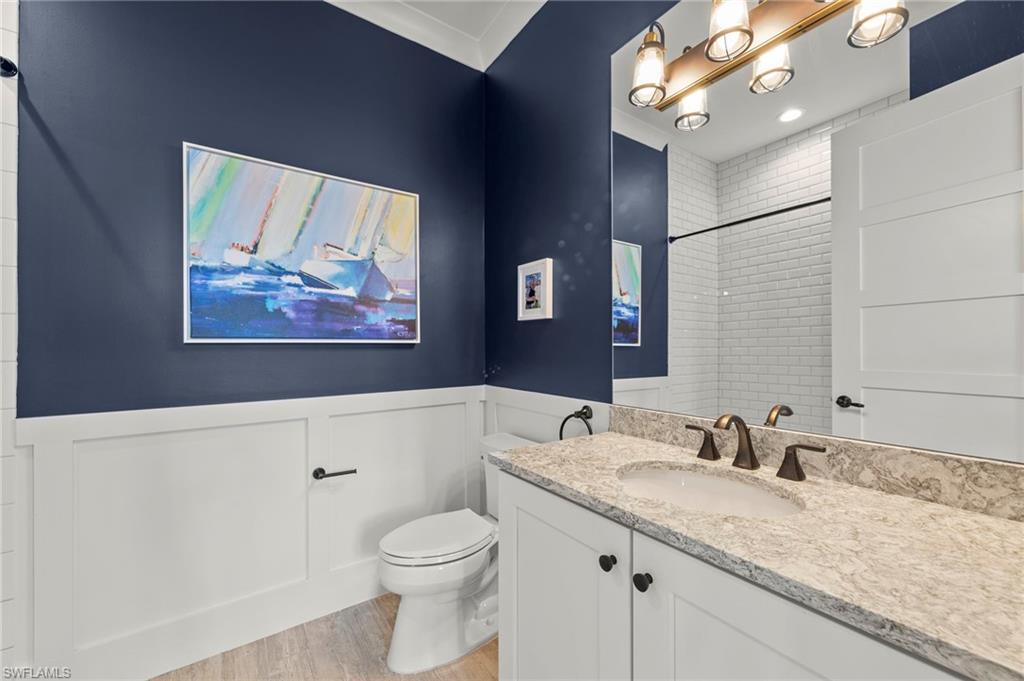 14785 Dockside Lane Naples, FL 34114 - Photo 20 of 50 Bathroom with vanity, light wood-style flooring, a wainscoted wall, a shower, and a decorative wall