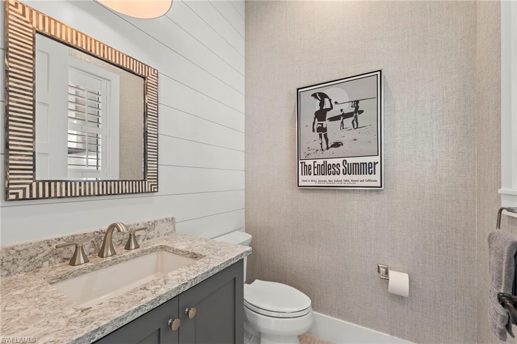 14785 Dockside Lane Naples, FL 34114 - Photo 26 of 50 Half bath with vanity and wooden walls New CUSTOM MIRROR (November 2018), New LIGHT FIXTURE (November 2018), New SHIPLAP WALL (May 2020), New WALLPAPER (June 2020)