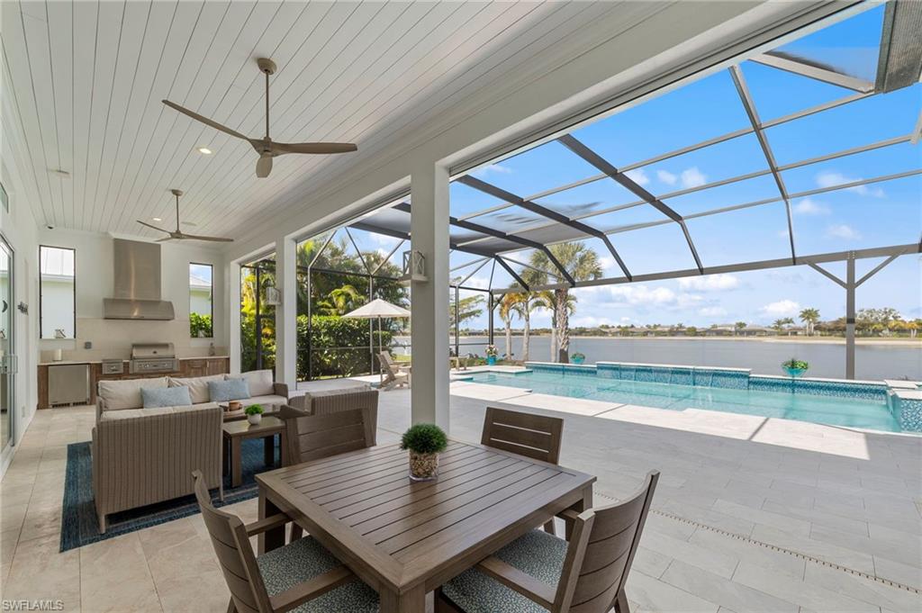 14785 Dockside Lane Naples, FL 34114 - Photo 33 of 50 Swimming pool featuring area for grilling, a patio area, a sunroom, a lanai, and an outdoor living / dining area New OUTDOOR KITCHEN (December 2018), New electric Storm Smart HURRICANE SHUTTERS (March 2019), New SHIPLAP CEILING & CROWN MOLDING (May 2020), New CEILING FAN (October 2024)