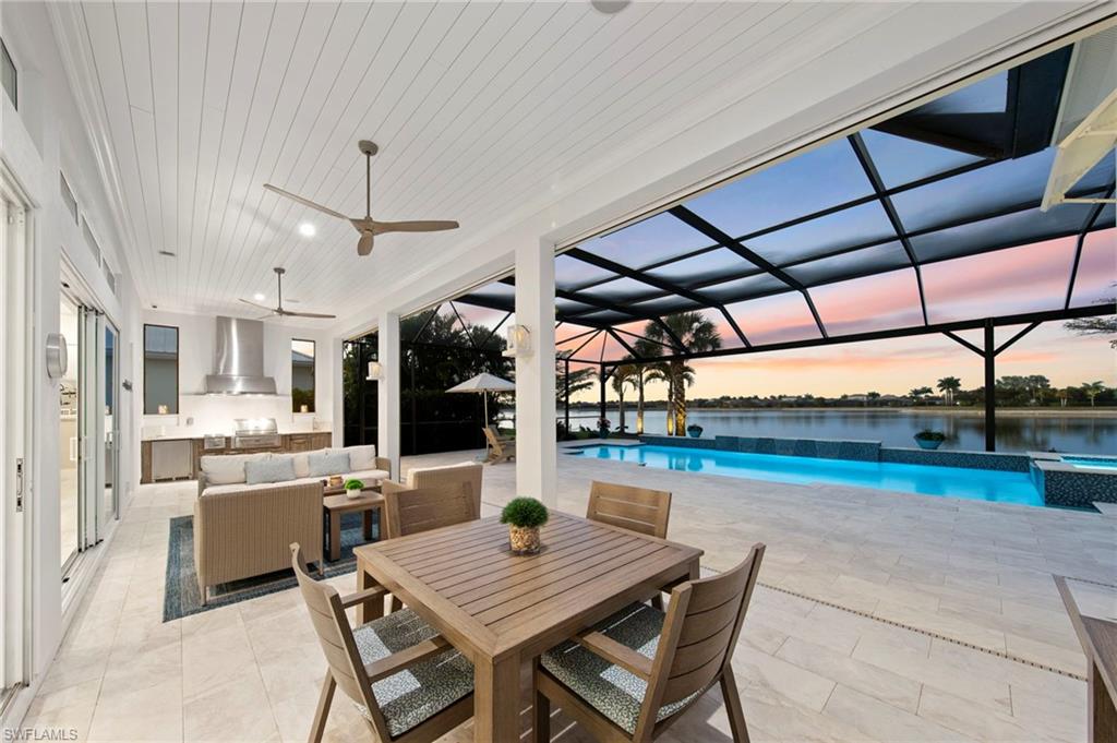 14785 Dockside Lane Naples, FL 34114 - Photo 35 of 50 Patio terrace at dusk with a lanai, a patio, ceiling fan, outdoor lounge area, and a pool with connected hot tub New OUTDOOR KITCHEN (December 2018), New LANDSCAPE LIGHTING (February 2019) New electric Storm Smart HURRICANE SHUTTERS (March 2019), New SHIPLAP CEILING & CROWN MOLDING (May 2020), New CEILING FAN (October 2024)