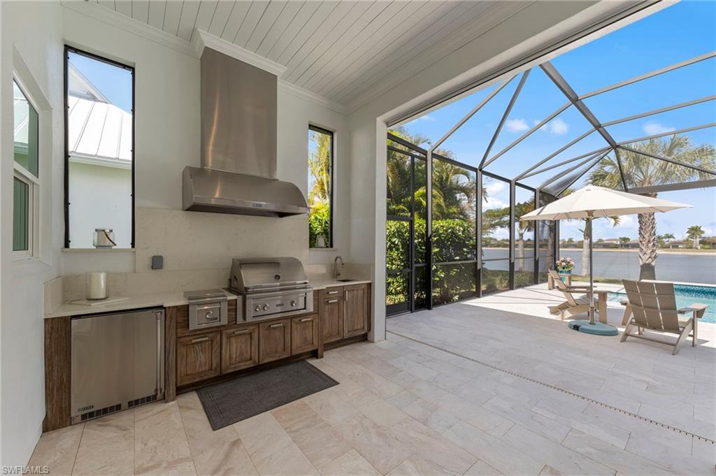 14785 Dockside Lane Naples, FL 34114 - Photo 36 of 50 View of patio with glass enclosure, area for grilling, a sunroom, an outdoor pool, and a water view New OUTDOOR KITCHEN (December 2018), New electric Storm Smart HURRICANE SHUTTERS (March 2019), New SHIPLAP CEILING & CROWN MOLDING (May 2020),