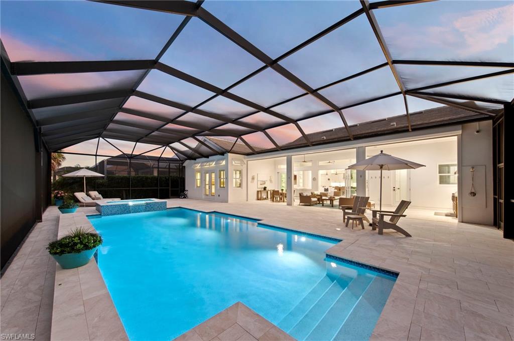 14785 Dockside Lane Naples, FL 34114 - Photo 40 of 50 Pool at dusk with a sunroom, a pool with connected hot tub, a patio area, and a lanai
