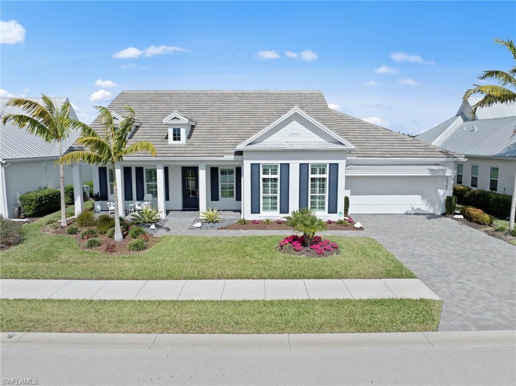 14785 Dockside Lane Naples, FL 34114 - Photo 4 of 50 View of front facade featuring a front yard, a porch, driveway, an attached garage, and a tile roof New VIDEO DOORBELL (November 2018), ROOF POWER WASHED (December 2022), New LANDSCAPING (December 2025)