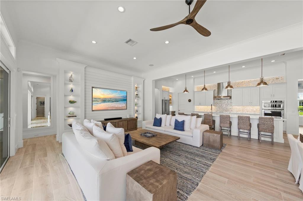 14785 Dockside Lane Naples, FL 34114 - Photo 7 of 50 Living room featuring crown molding, wood tiled floors, ceiling fan, recessed lighting, and built in features New MOUNTED TV & SONOS SOUND BAR (November 2018), New KITCHEN PENDANTS (November 2018), New SHIPLAP BUILT-IN & WALLS (May 2020, New KITCHEN INTERIOR PAINT (July 2023)New CEILING FAN (October 2024)