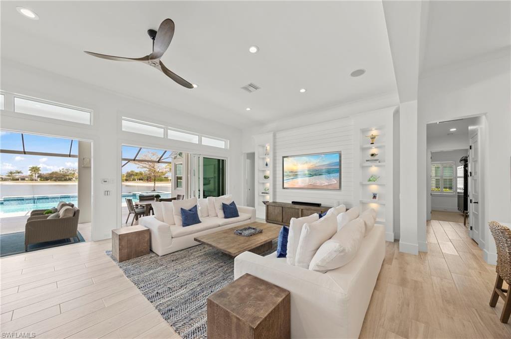 14785 Dockside Lane Naples, FL 34114 - Photo 8 of 50 Living room with a sunroom, recessed lighting, light wood-type flooring, a ceiling fan, and built in features New MOUNTED TV & SONOS SOUND BAR (November 2018), New SHIPLAP BUILT-IN & WALLS (May 2020), New CEILING FAN (October 2024)
