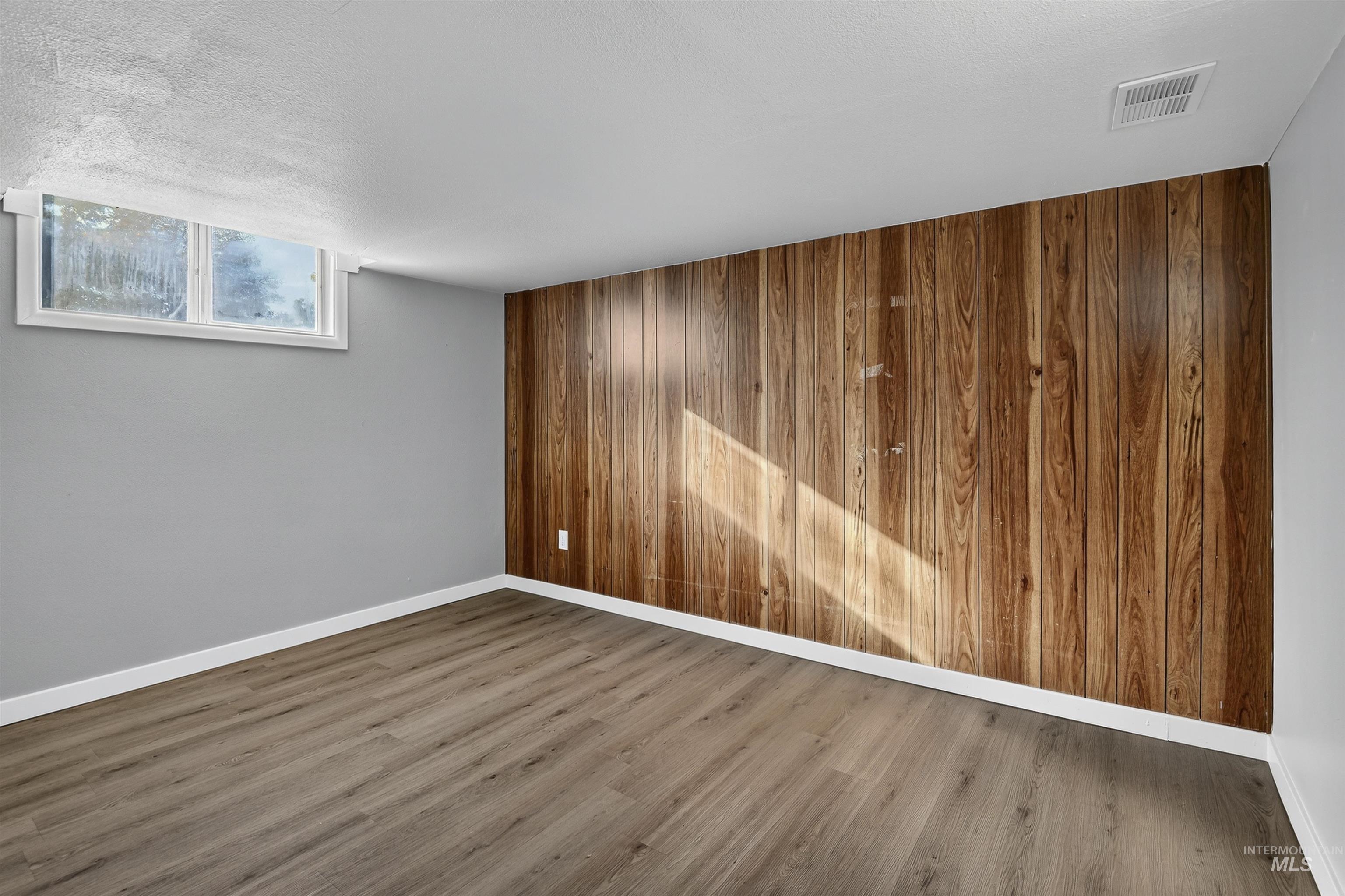 2118 West Targee Street Boise, ID 83705 - Photo 12 of 25 Spare room featuring wooden walls, wood finished floors, and a textured ceiling