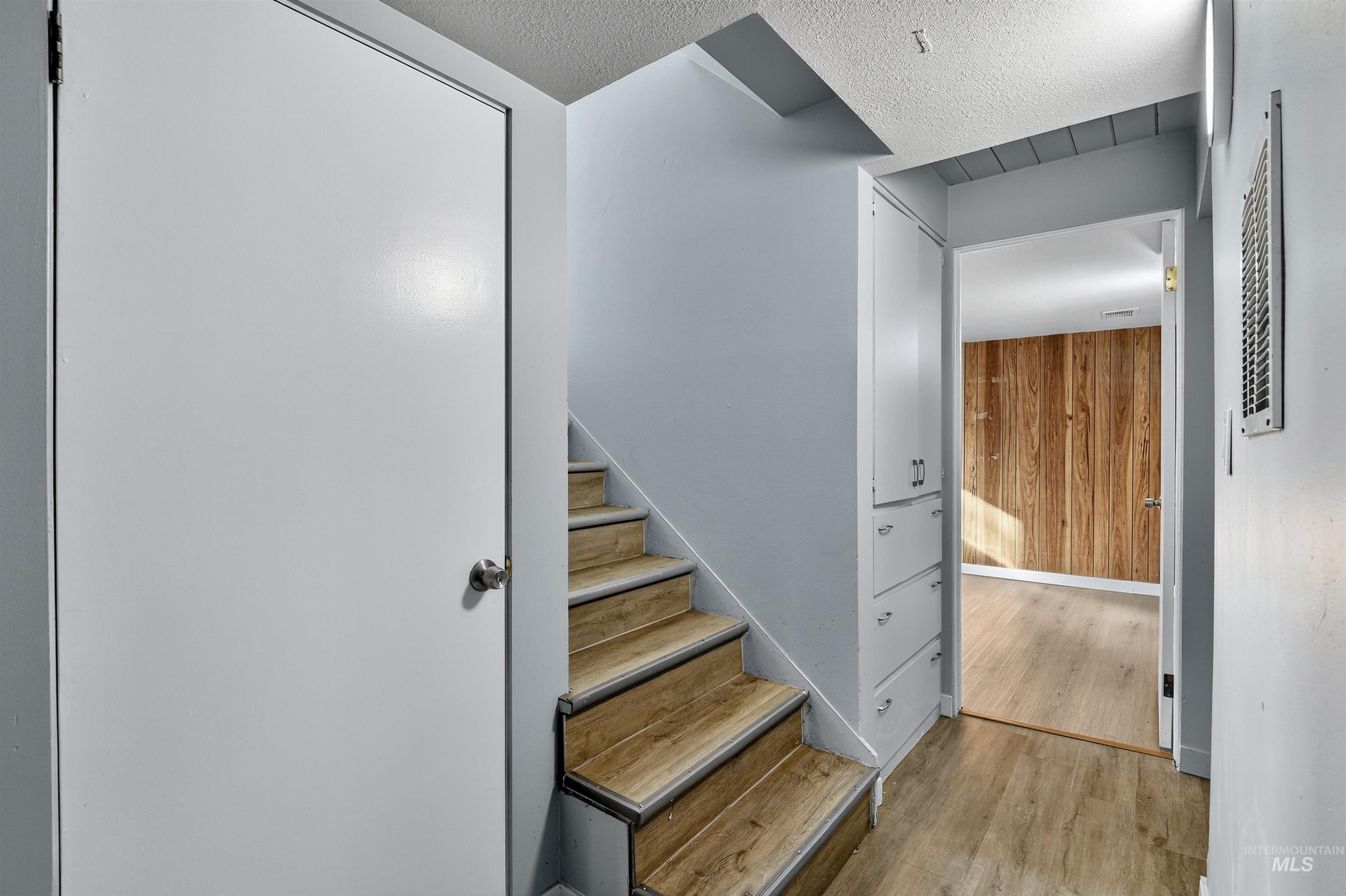 2118 West Targee Street Boise, ID 83705 - Photo 14 of 25 Stairway featuring wood finished floors, wooden walls, and a textured ceiling