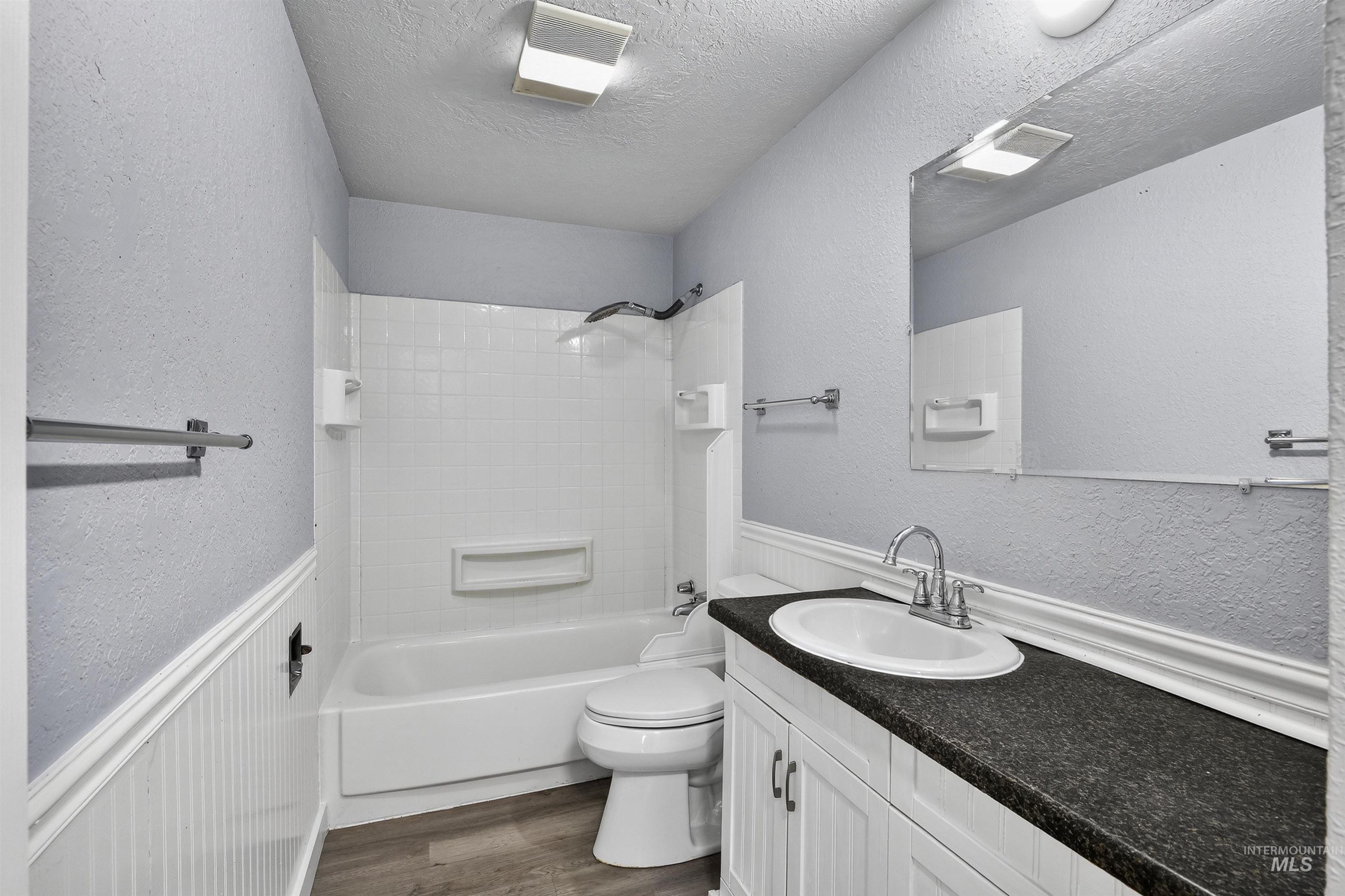 2118 West Targee Street Boise, ID 83705 - Photo 15 of 25 Full bath with a textured wall, wainscoting, shower / bathtub combination, vanity, and dark wood-style floors