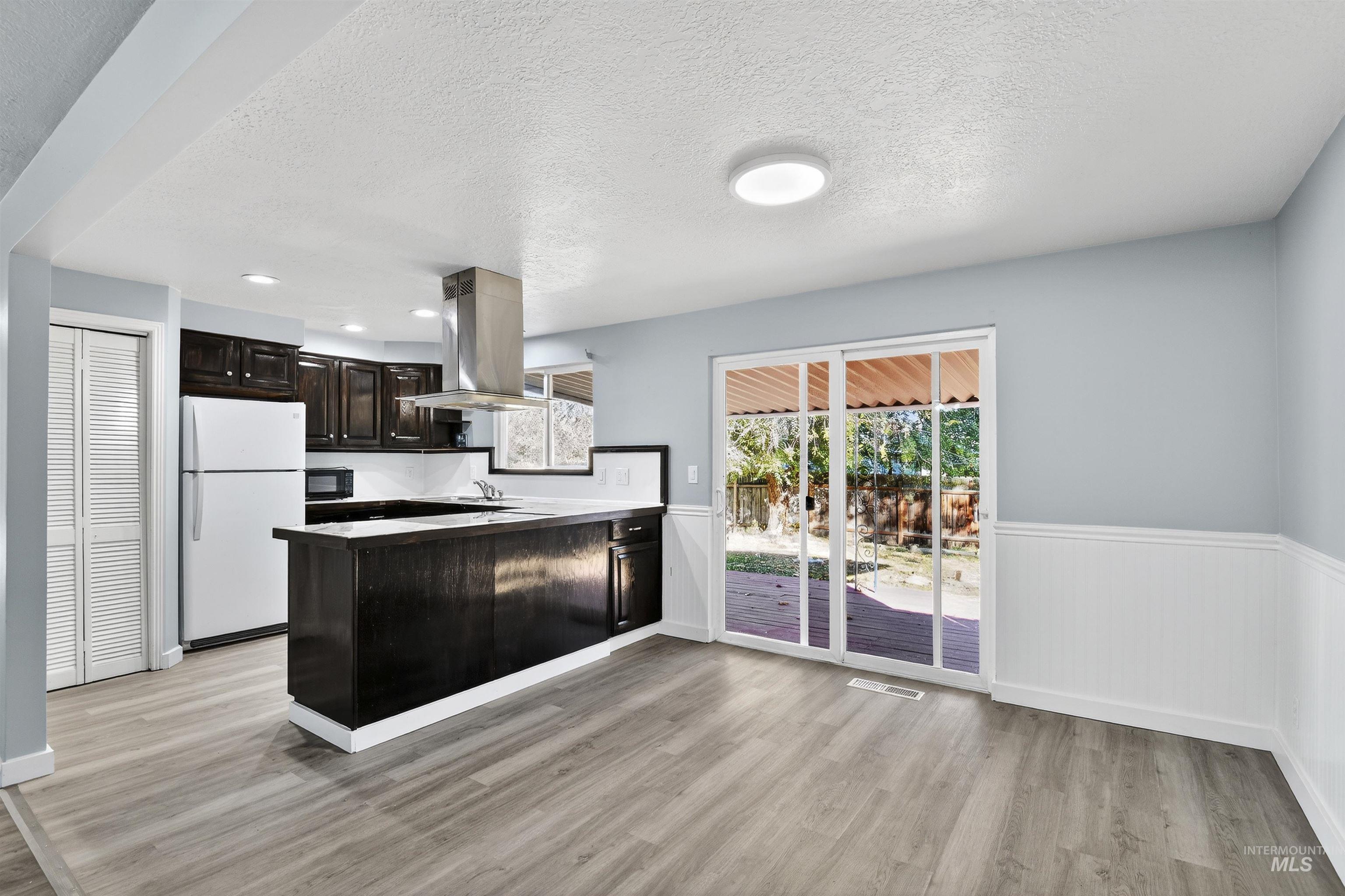 2118 West Targee Street Boise, ID 83705 - Photo 6 of 25 Kitchen featuring a peninsula, freestanding refrigerator, dark brown cabinets, a textured ceiling, and light wood-style floors