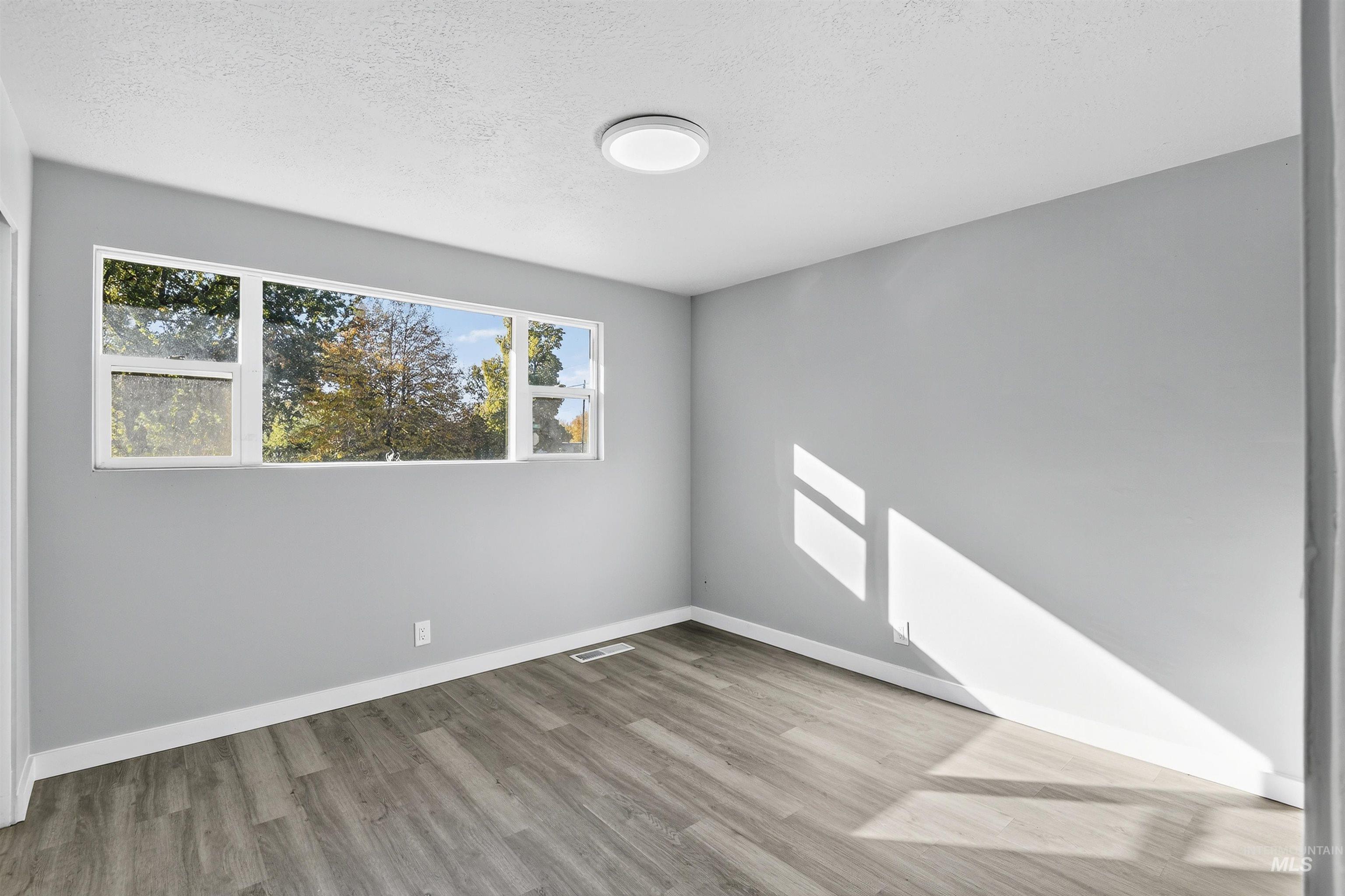 2118 West Targee Street Boise, ID 83705 - Photo 10 of 25 Unfurnished room featuring healthy amount of natural light, light wood-style flooring, and a textured ceiling
