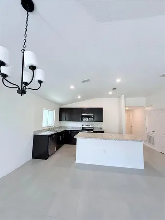 a living room with stainless steel appliances kitchen island a chandelier and a couch