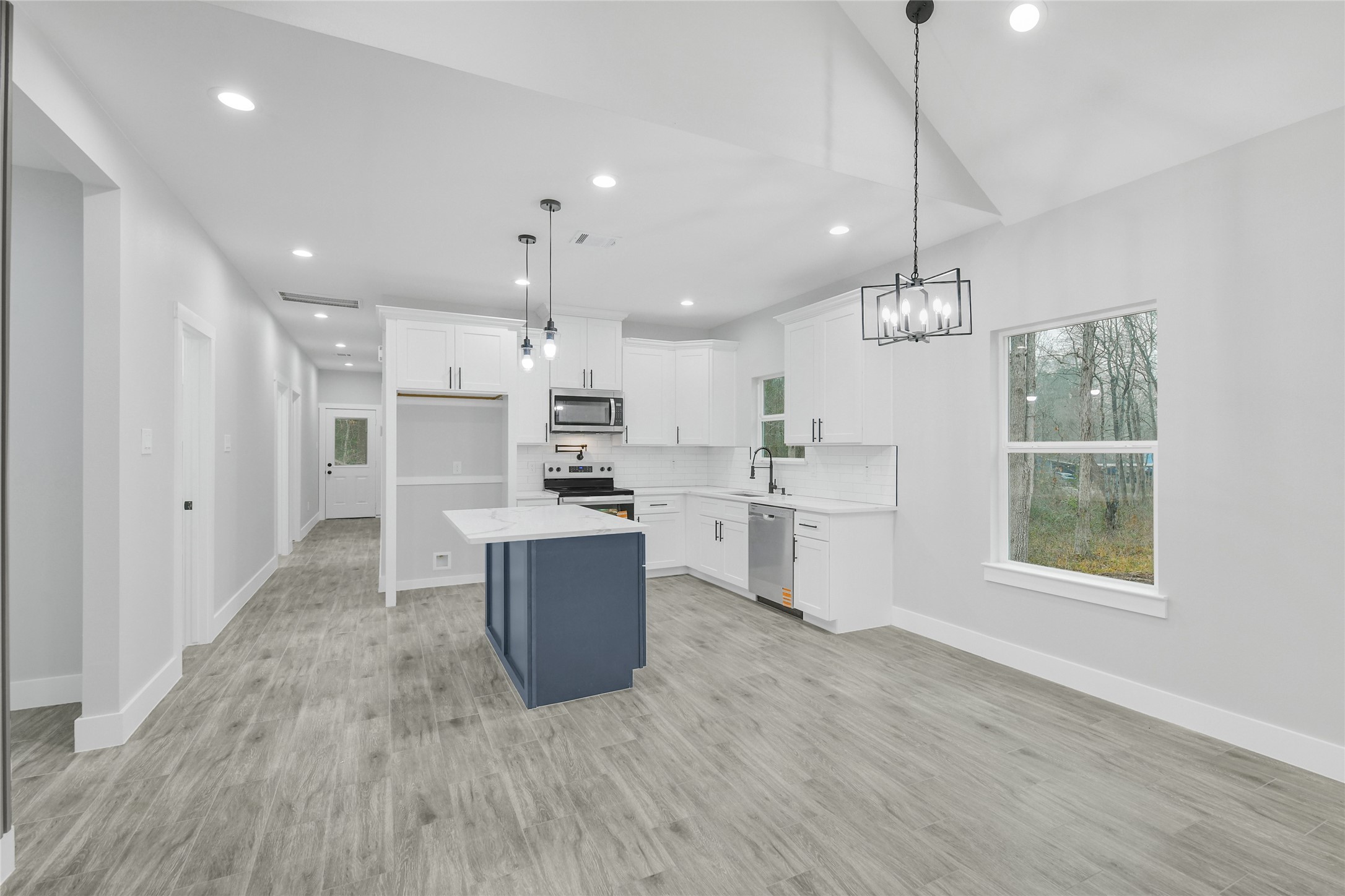 15117 Austin Road Willis, TX 77378 - Photo 8 of 35 a kitchen with stainless steel appliances kitchen island granite countertop a refrigerator a sink dishwasher a stove and white cabinets with wooden floor