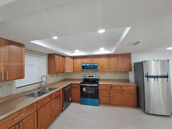 a kitchen with stainless steel appliances granite countertop a refrigerator sink and wooden cabinets