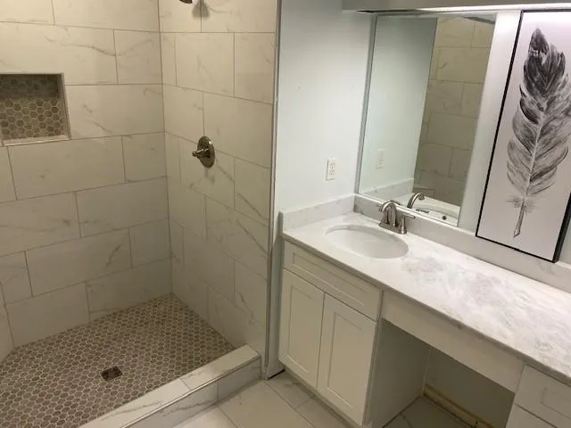 a bathroom with a granite countertop sink a shower and a mirror