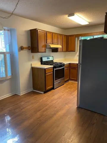 a large kitchen with stainless steel appliances wooden cabinets a stove a microwave and a refrigerator