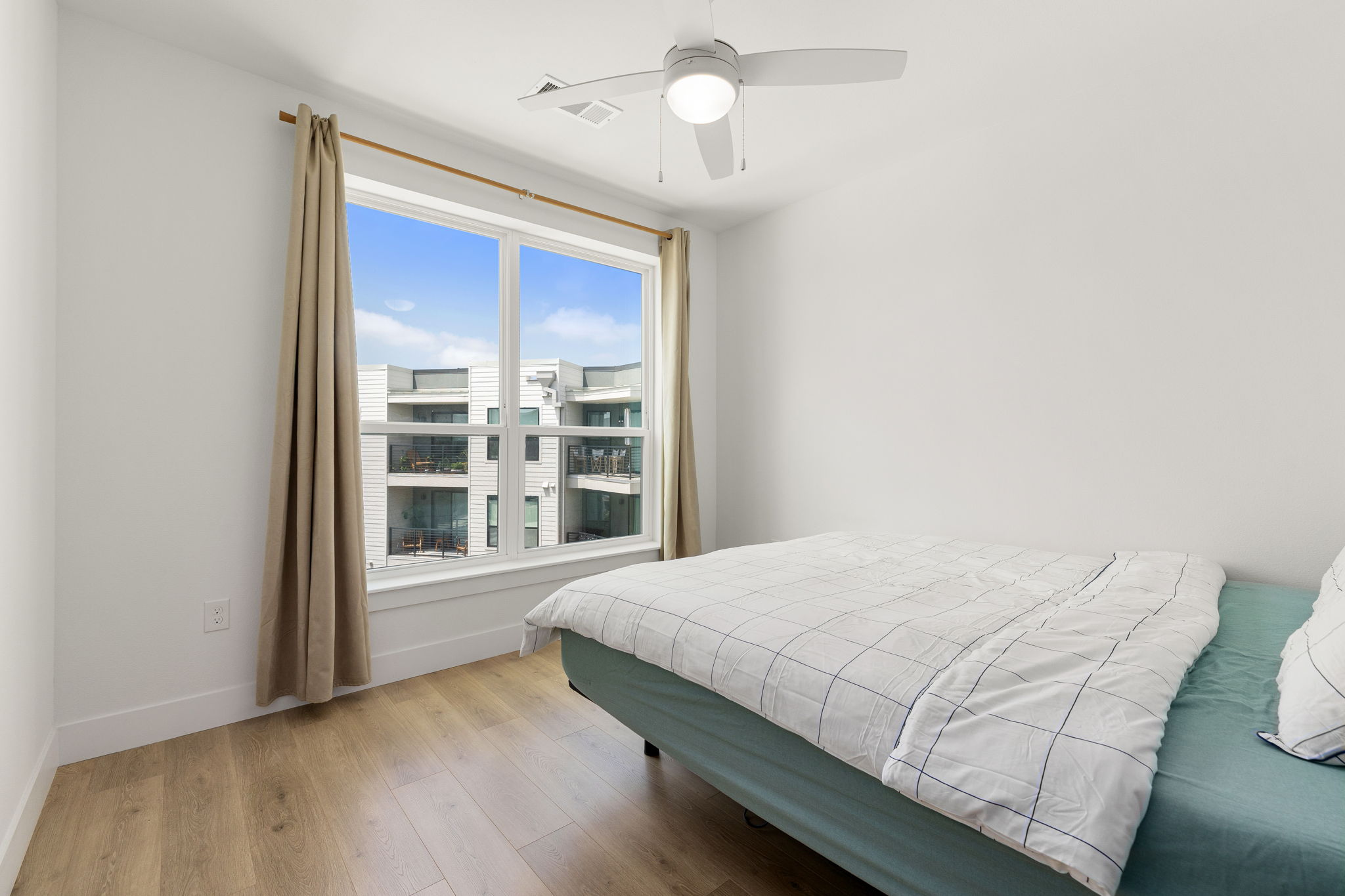 1701 Simond Avenue, Unit 612 Austin, TX 78723 - Photo 15 of 40 Bright bedroom featuring wood-finish flooring, a contemporary ceiling fan, and a large window with white trim