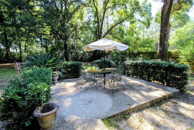 a view of a table and chairs under an umbrella in backyard