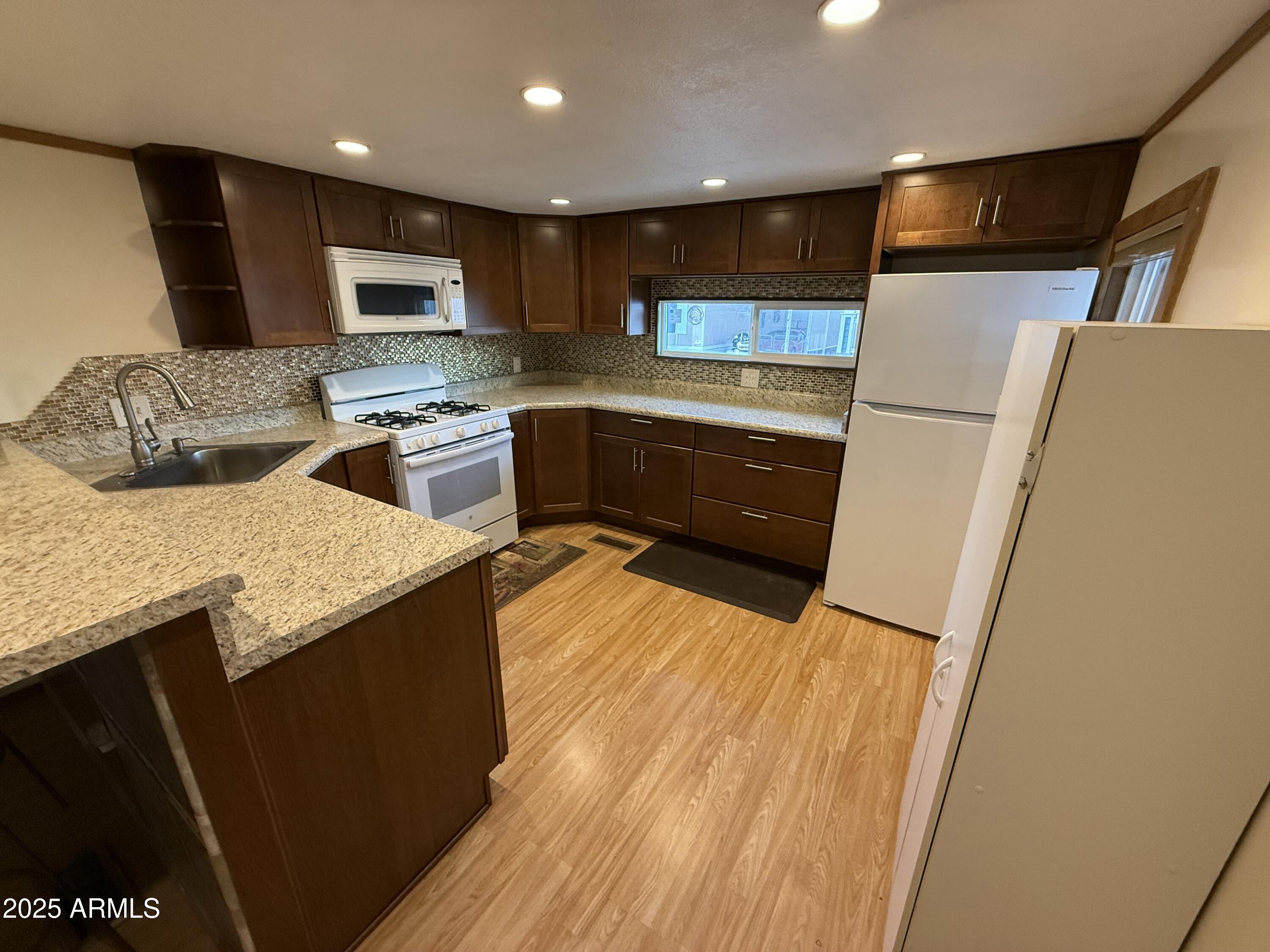 535 South Alma School Road, Unit 91 Mesa, AZ 85210 - Photo 8 of 26 a kitchen with stainless steel appliances a refrigerator a sink a stove a microwave and wooden cabinets