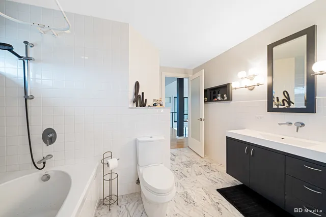 a spacious bedroom with a bed a chandelier and windows