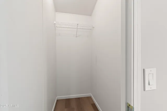 an empty room with wooden floor closet and fan
