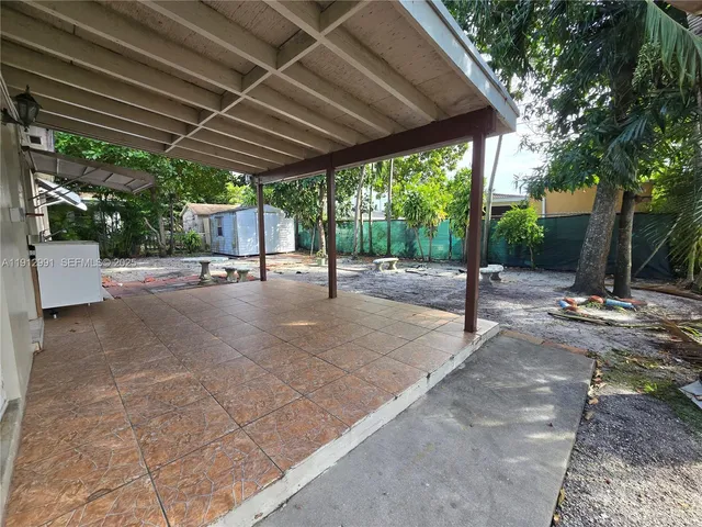 a palm tree sitting in a yard with a large trees
