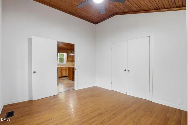 a view of empty room with wooden floor and fan
