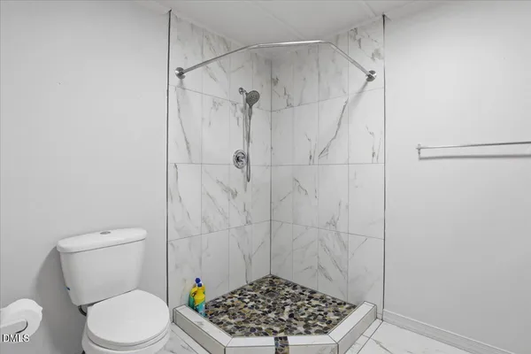 a bathroom with a sink a toilet a window and shower