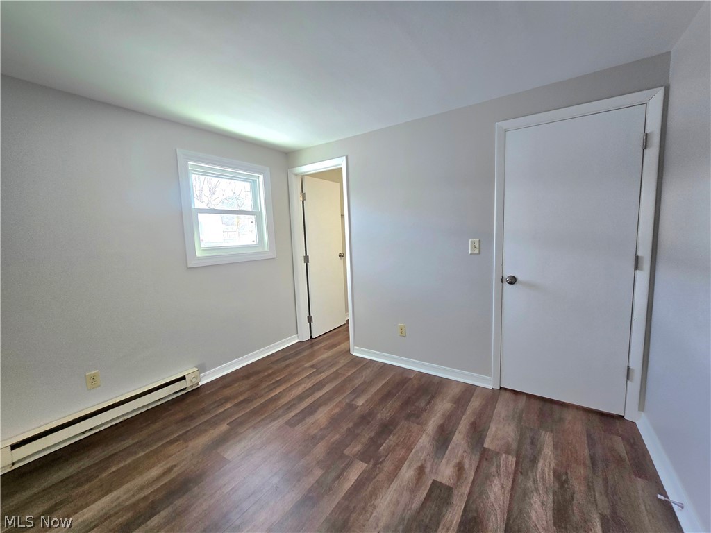 909 Garden Road Zanesville, OH 43701 - Photo 4 of 8 Unfurnished bedroom featuring a baseboard heating unit and dark wood-style floors
