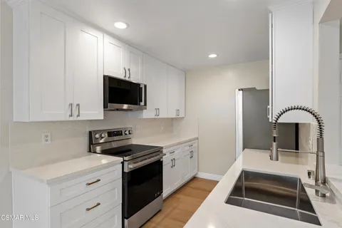 a kitchen with stainless steel appliances granite countertop a sink a refrigerator and a stove