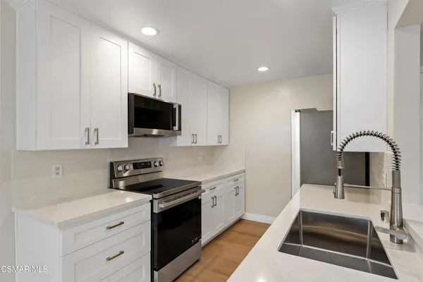 a kitchen with stainless steel appliances granite countertop a sink a refrigerator and a stove